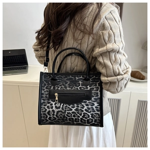 Close-up of leopard print crossbody bag with black handles and front zipper detail