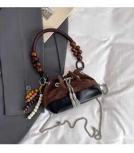 Dettaglio borsa a secchiello vintage in pelle scamosciata con manico di legno