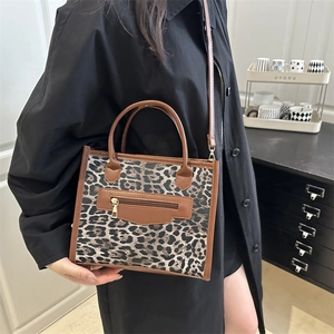 Fashionable leopard print large tote bag with brown leather handles and gold zipper detail