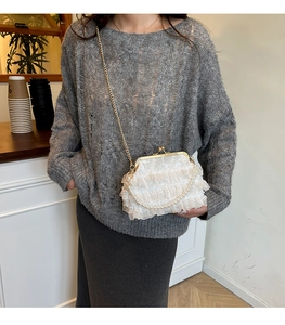 White lace pleated evening bag with pearl handle and metal chain shown on a model
