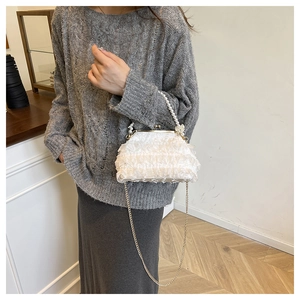 White lace handbag with pearl handle and gold chain strap shown on model's side