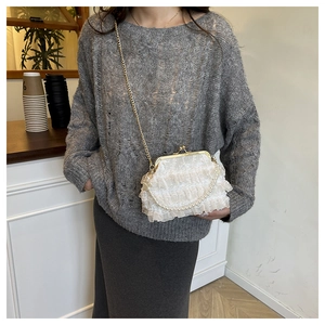 Lace ruffle clutch with pearl handle and gold chain strap shown on model shoulder