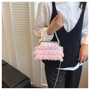 Detail of pink lace shell bag with pearl handle and metal chain on a model