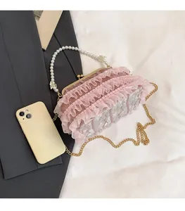 Pink lace evening bag with pearl handle and metal chain shown next to a smartphone for scale