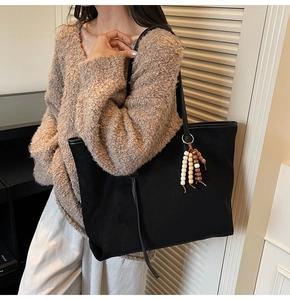 Detail of minimalist black matte tote bag featuring stylish wooden bead tassel accessory