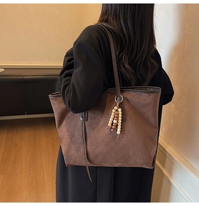 Detail of coffee suede tote bag featuring grid embossed texture and wood bead charm