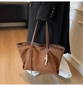 Detail of dark brown faux suede tote bag featuring checkerboard embossing and wood bead charm