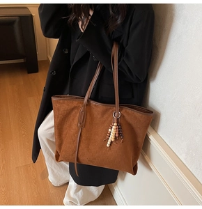 Detail of brown faux suede tote bag with geometric texture and wooden bead charm