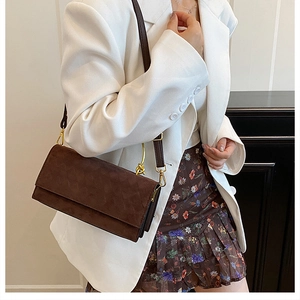Brown faux suede crossbody bag styled with a white blazer for a chic commuting look