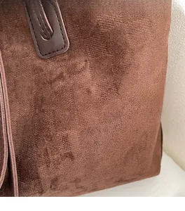 Close-up of brown suede tote bag with reinforced leather strap and neat stitching detail