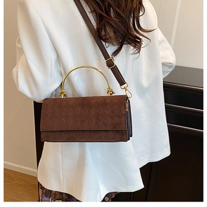 Detail of dark brown suede crossbody bag with quilted pattern and gold round metal handle