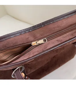 Detail of dark brown matte tote bag with gold zipper and striped interior lining