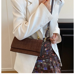 Detail of dark brown quilted handbag with gold metal handle and fine leather strap