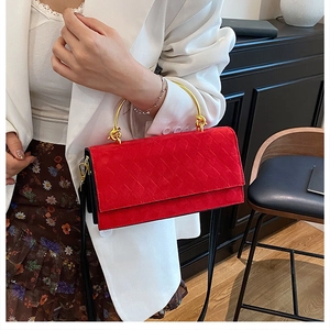 Detail of red quilted suede crossbody bag with elegant gold circular metal handle