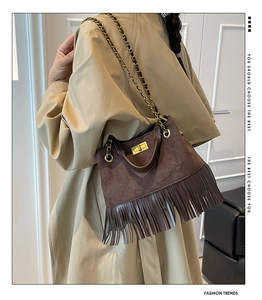 Détail d'un sac en daim matelassé marron foncé avec franges et chaîne dorée