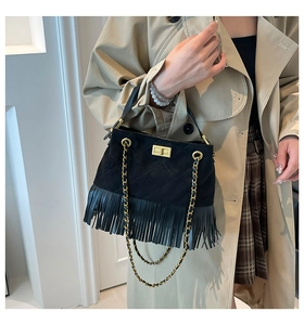 Détail du sac bandoulière matelassé noir à franges avec chaîne dorée porté par un mannequin