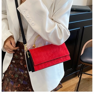 Close-up of red suede quilted handbag featuring a modern golden ring handle