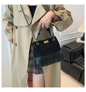 Détail d'un sac à franges en daim noir avec boucles dorées et bandoulière chaîne