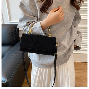 Detail of quilted black handbag with artistic gold metal handle and long shoulder strap