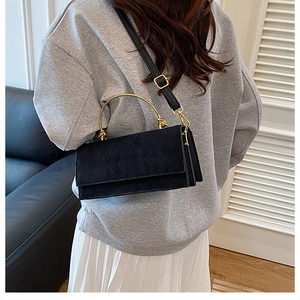 Detail view of black quilted crossbody bag with stylish gold circular metal handle