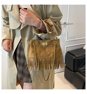 Détail d'un sac bandoulière en daim marron avec de longues franges et chaîne dorée