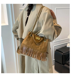 Détail du sac bandoulière en daim matelassé marron avec pompons et chaîne dorée