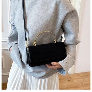 Macro detail of black quilted crossbody bag with golden metal handle and matte texture