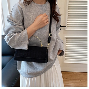 Close-up of quilted black crossbody bag with golden metal handle on casual outfit