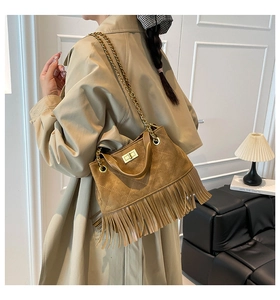Détail d'un sac matelassé en daim marron avec de longues franges et un fermoir doré