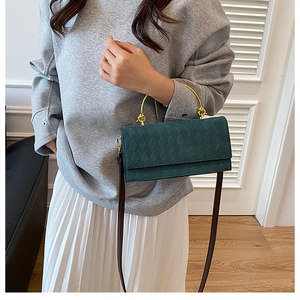Fashionable dark green quilted handbag with gold handle worn as a crossbody bag