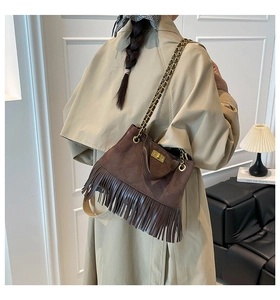 Détail du sac à franges en daim marron foncé avec surpiqûres losanges et fermoir doré