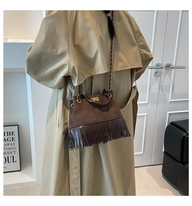 Détail d'un sac matelassé marron foncé avec franges en cuir et bandoulière chaîne dorée