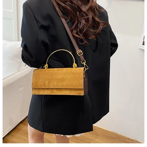 Detail of ginger yellow quilted suede crossbody bag with elegant gold top handle