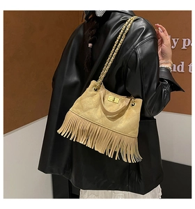 Détail d'un sac à main beige matelassé avec de longues franges et une chaîne dorée
