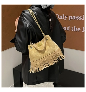Détail du sac à franges matelassé beige clair avec bandoulière chaîne dorée sur l'épaule