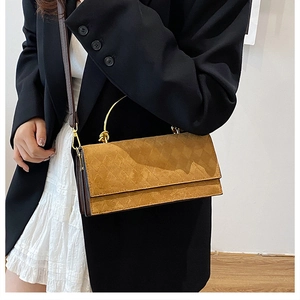 Close-up of a camel-colored quilted crossbody bag with golden metal handle and strap