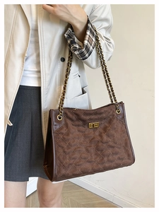 Détails du sac en daim marron avec fermoir doré, matelassage et bandoulière en chaîne