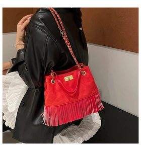 Détail d'un sac bandoulière rouge matelassé avec franges et chaîne dorée