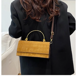 Detail of a mustard yellow quilted crossbody bag with stylish gold semi-circular handles