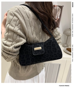 Détail du sac porté épaule imprimé léopard noir avec boucle métallique sur un pull