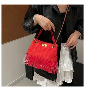 Détail du sac bandoulière en daim matelassé rouge avec franges et chaîne dorée