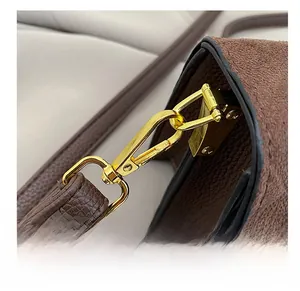 Detail shot of the golden metal hook and D-ring on a brown suede crossbody handbag