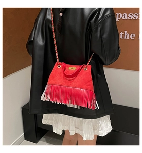 Détail du sac bandoulière matelassé rouge avec de longues franges et chaîne dorée