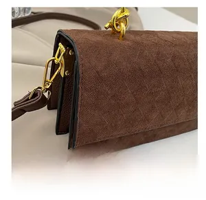 Detail of dark brown matte flap bag featuring gold chain and triple-layered side structure