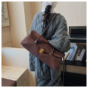 Detail of vintage brown suede bowling bag with gold buckle on a model in an office