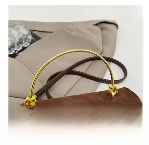 Detail of brown suede tote with a golden semi-circular metal handle and knot hardware