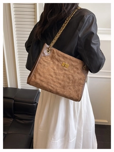 Detail shot of brown frosted quilted tote bag with golden twist lock and chain strap