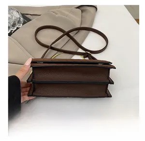 Detail view of brown lychee leather handbag bottom with reinforced black edges