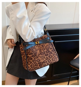 Close-up of leopard print bucket bag with gold twist lock on a beige blazer model