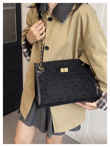 Détail du sac cabas matelassé noir en daim avec chaîne dorée et fermoir rotatif en métal